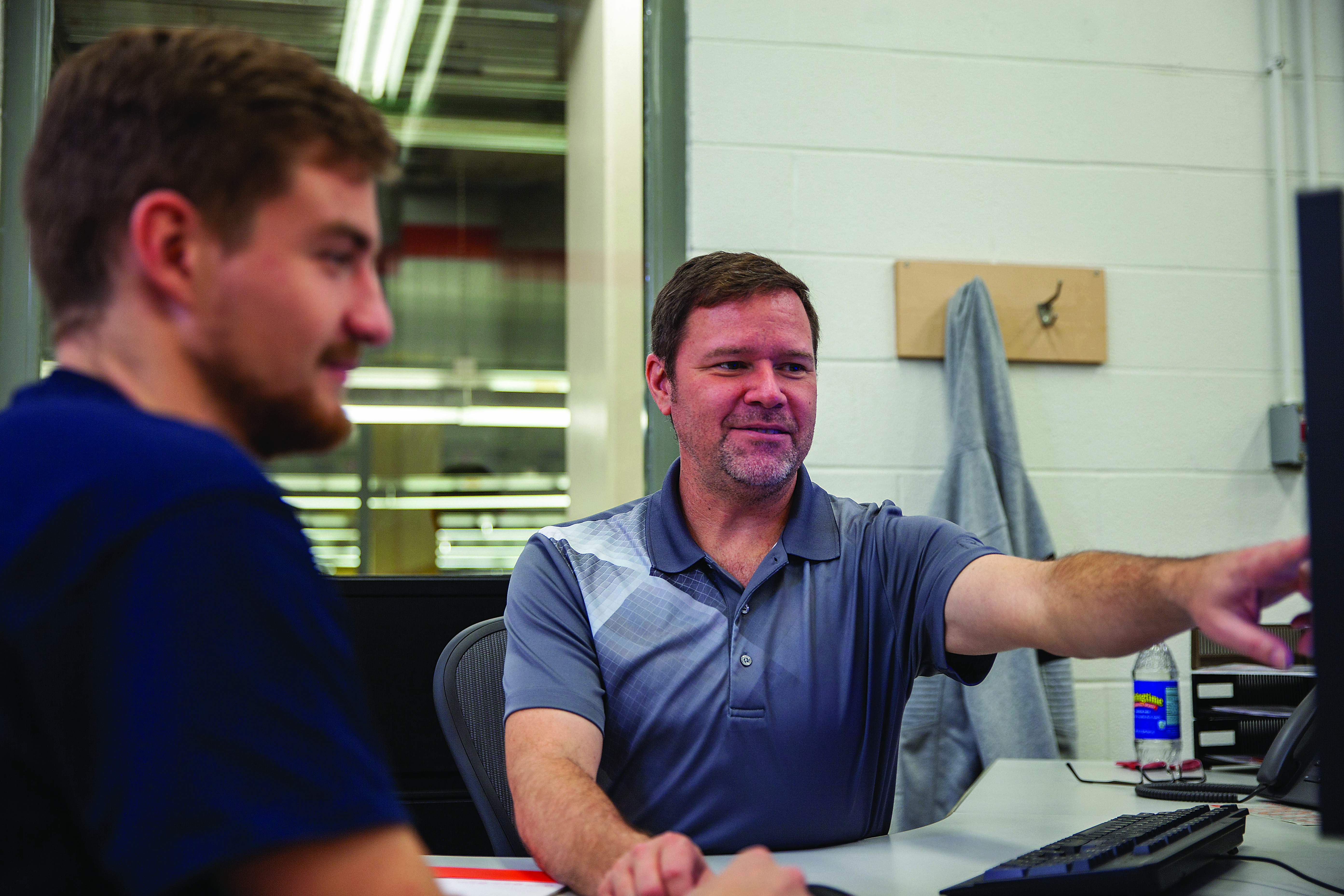 Apprenticeship trainer Jim Neal (above) works with a student at Blum’s factory in North Carolina.