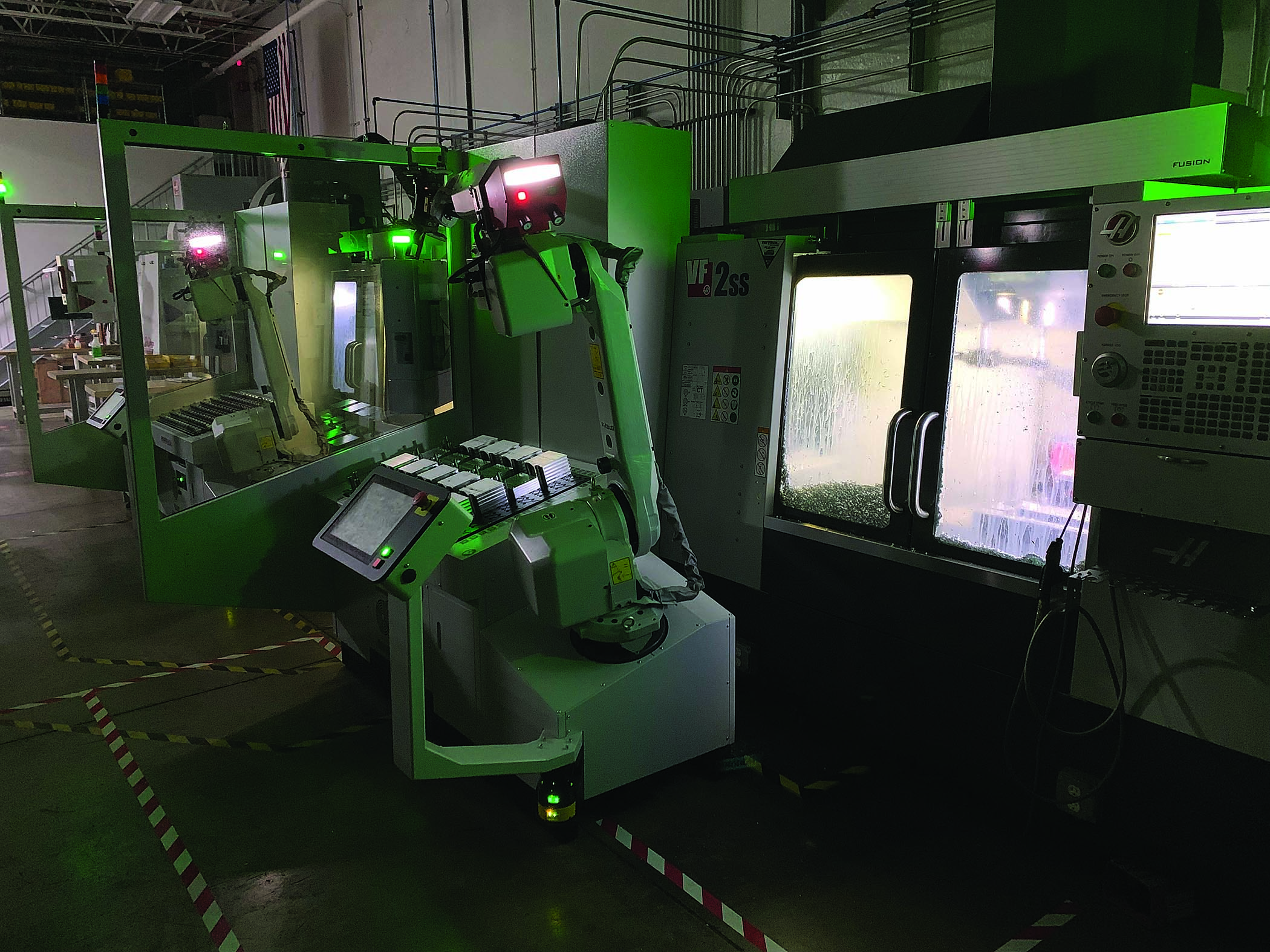 During a night shift, two Mill-Assist systems with traditional Fanuc industrial robots tend Haas VF-2SS CNC mills unattended.