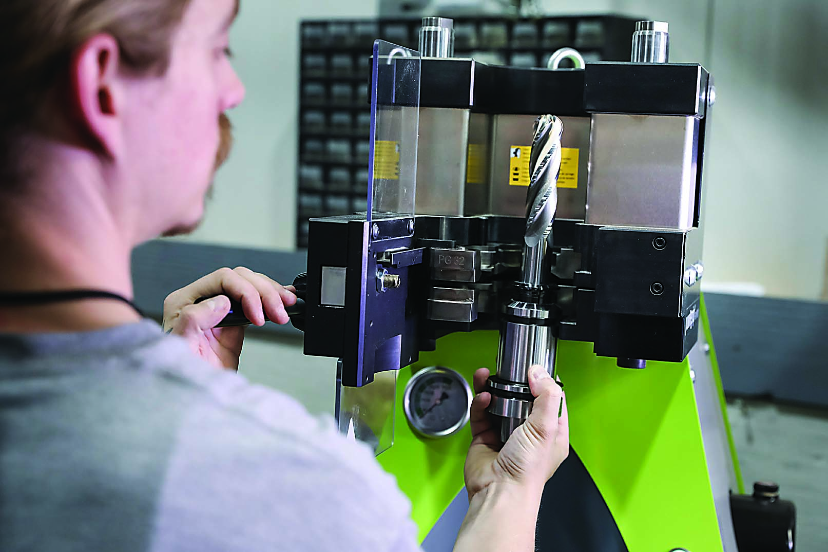 Noah Maraziti (left), lead CNC machinist at Symmetrix Composite Tooling, removes a tool and holder assembly from the powRgrip unit.