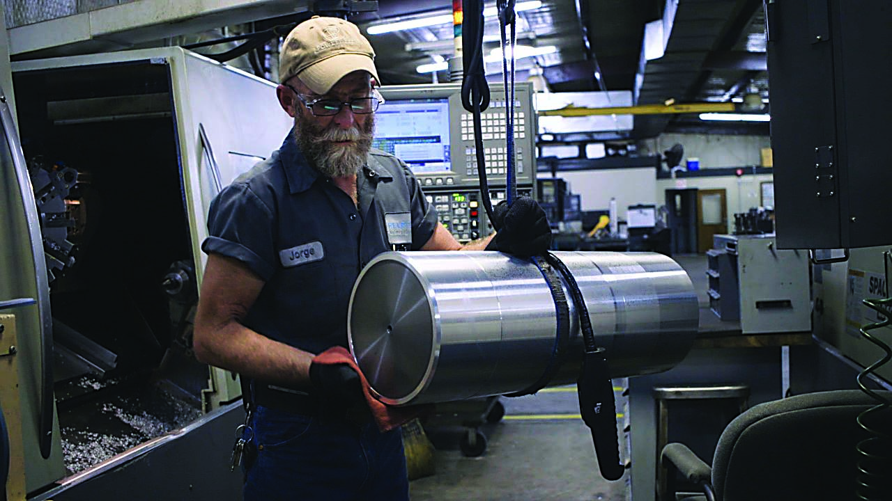 Machinist Jorge Diaz loads a workpiece into a turning center.