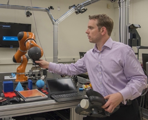 NIST engineer Jeremy Marvel adjusts a robotic arm used to study human-robot interactions.