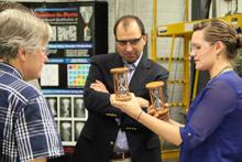 Metallugists Anderson (left) and White demonstrate the metal powder's properties to a visitor. Credit: Ames Laboratory