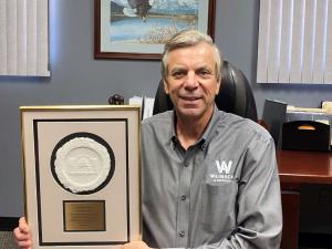 Kevin Weinacht, company founder, holds to the Eriez Merlin award.