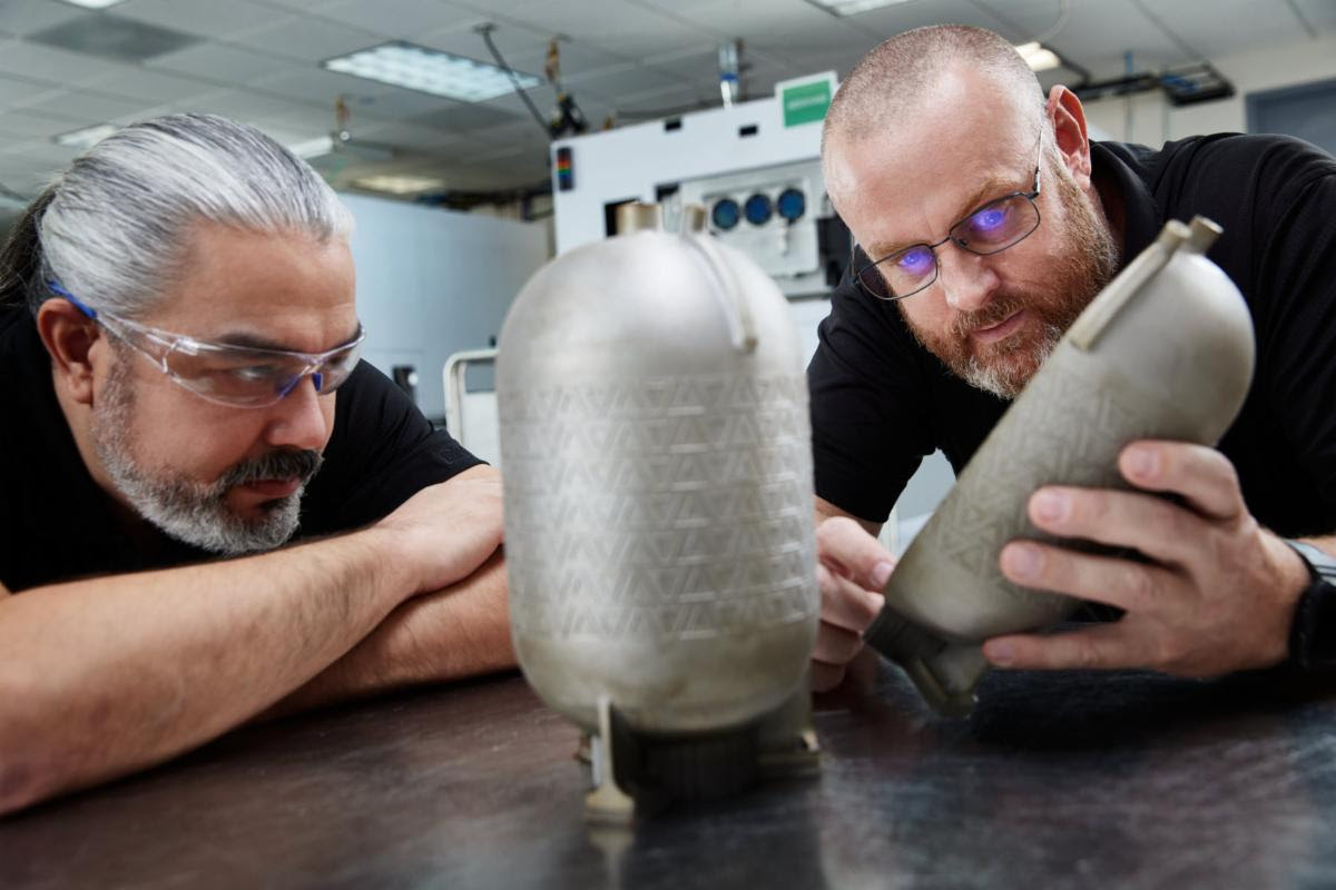 Engineers examine a titanium fuel tank printed on a VELO3D additive manufacturing system with no internal supports.